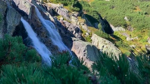 View of a beautiful waterfall and the green nature surrounding in a panning shot.