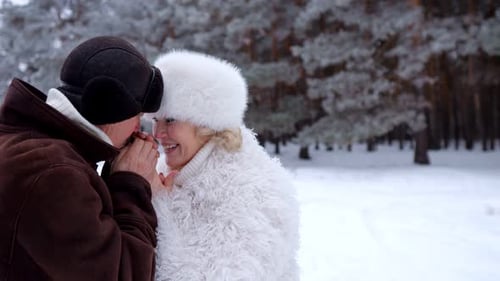 Man Warms Smiling Lady Hands with Breath in Winter Park