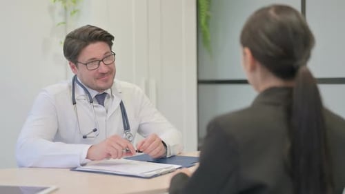 Adult Doctor Consults With Patient in Clinic Office