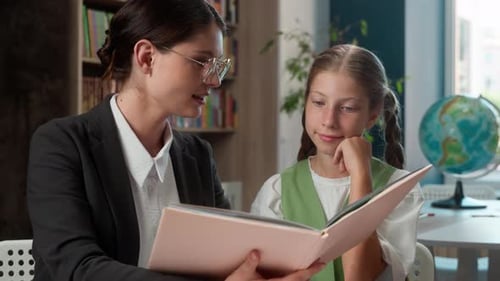 Teacher Reading Book with Student in Classroom