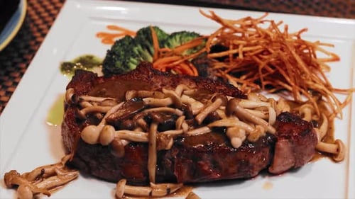 Close up angus steak with mushroom sauce on a white plate. On a black table of a luxury restaurant.