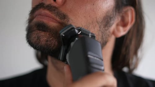 Man Shaving Beard with Electric Razor in Close Up