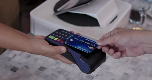 Video showing close-up of credit card being swiped through payment terminal held by senior Asian...