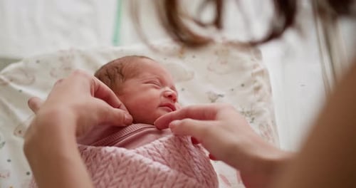 Caring Mother Comforts Newborn Baby at Home