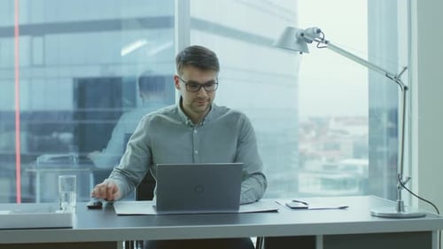 Successful Young Businessman Works on a Laptop in His Modern Office. Smart Young Man Working for a