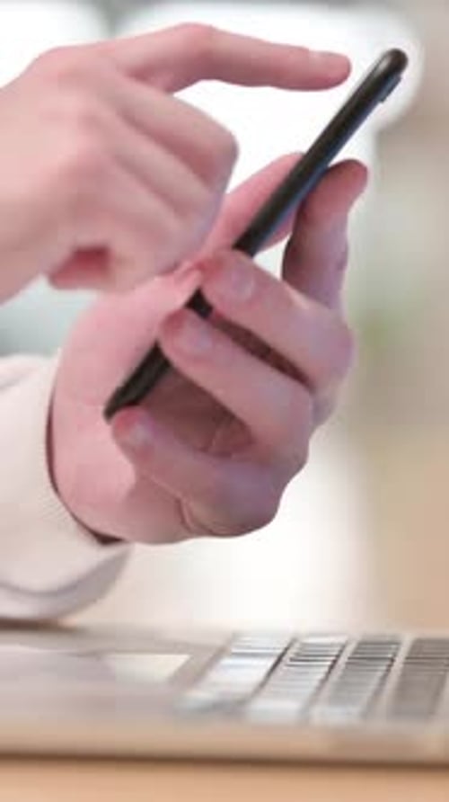 Finger Taps Phone Screen over Laptop Keyboard