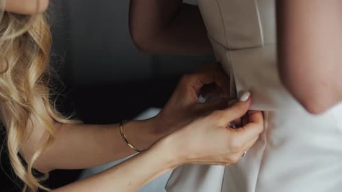 Bridesmaid Zipping Up Wedding Dress of Bride
