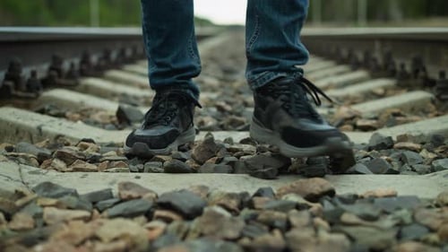 CloseUp of Legs Walking on Rocky Railway Tracks with Blurred Background