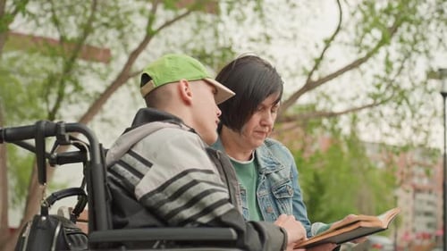 Teen and Woman Reading Book Together Outdoors