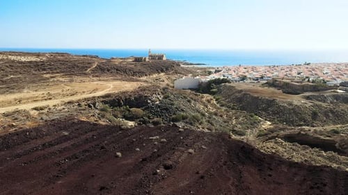 Forwarding Aerial Dolly Shot Over Desert Land by the Outskirts of Large Village, Spain Europe