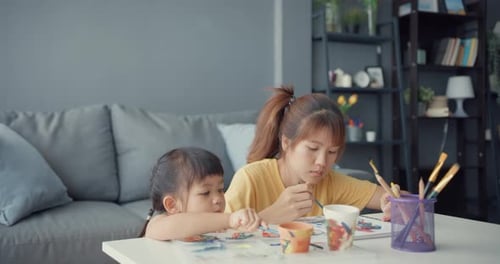 Young Girl and Young Adult Painting Together Indoors