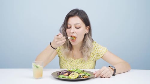 Young Woman Enjoys Healthy Salad at Table