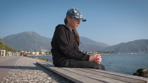 Ein trauriges Mädchen schaut auf die Meereslandschaft und fängt an zu lächeln