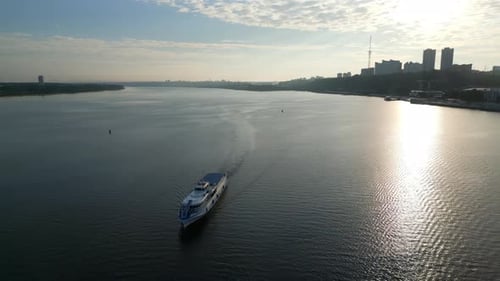 Passenger Ferry Navigating River at Sunrise Near Cityscape Clip