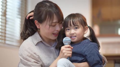 Mother and Daughter Singing into Microphone Together