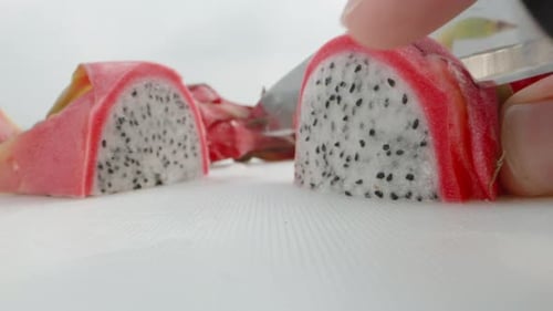 Pitahaya or dragon fruit with white flesh, I cut a piece with a knife. Super close-up.