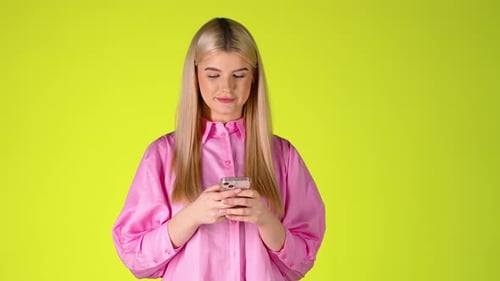 Pretty Blonde Woman Holding a Smartphone, Browsing Scrolling The Touch Screen, Colorful Studio Shot