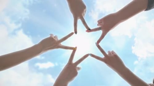 Menschen formen Sternform mit ihren Finger gegen den blauen Himmel mit leuchtenden Sonnenstrahlen