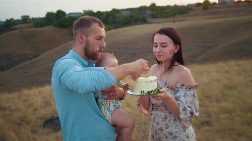 Happy Family with Baby Celebrate First Year Eat Cake in Field at Sunset Autumn and Lifestyle