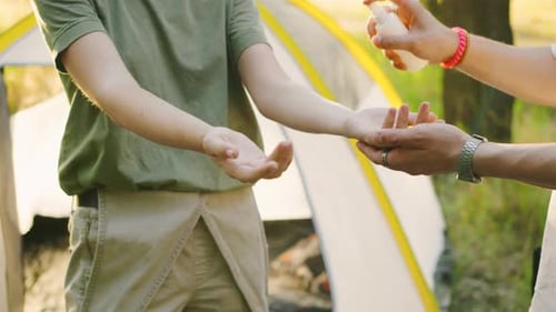 A Group of Young Tourists in a Beautiful Forest Applying Mosquito Repellent at Sunset Against the