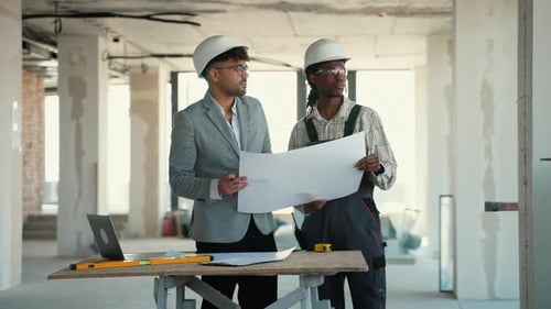 Architect and Foreman Discussing Blueprint in Unfinished Building