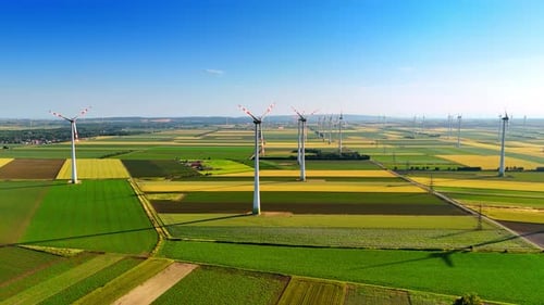Colorful patched field with wind farms. Vast plantations with numerous wind mills working on.