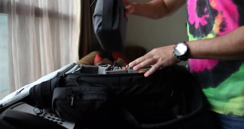Adult Packing Photography Gear in Hotel Room