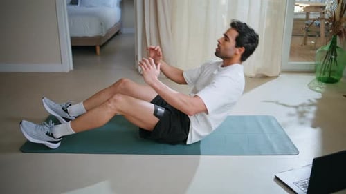 Man Pumping Abs Muscles on Sport Mat at Apartment Floor Athletic Guy Workout