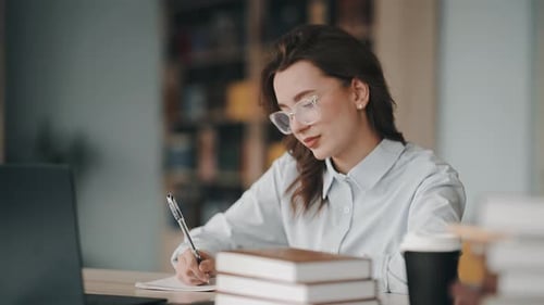 Young female student writing notes in a university library