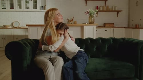 Affectionate Mother and Daughter Hugging on Green Sofa