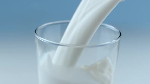 Pouring milk into a glass on blue background