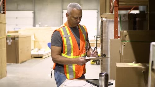 Confident african american warehouse manager smiles holding clipboard