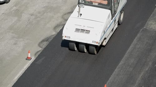 Asphaltverdichtung mit pneumatischem Straßenwalzenfahrzeug während der Pflasterung von Stadtstraßen, gesehen von