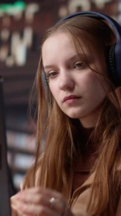 Vertical Video Young Girl Listening to Educational Documentary on Laptop and Taking Notes
