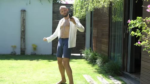 Young Man Listening to Music and Dancing in Garden Adult