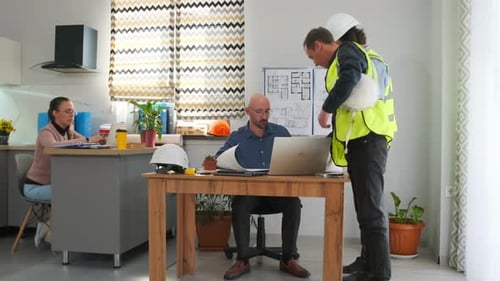 Builders Discuss Project Details with Manager in Office