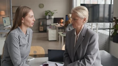 Young Female Employee Talking to Mature Female CEO in Office