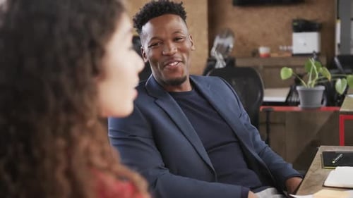 Two happy diverse creative colleagues in discussion in casual office, slow motion