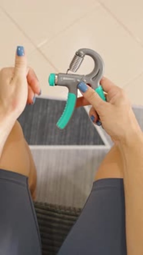 Vidéo verticale. Vue aérienne d'une femme ajustant le renforçateur de poignée assise sur une chaise
,
