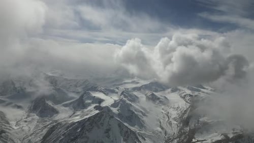 Paisagem de montanhas nevadas revela picos dramáticos e nuvens inconstantes, mostrando a beleza da natureza