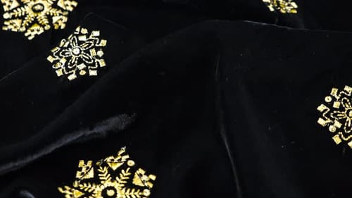 Luxurious black silken textile fabric velvet decorated with gold embroidery. Textile background