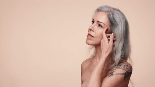 Mature Woman with Gray Hair Touches Her Face