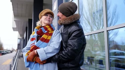 Couple Sharing a Warm Embrace Outside a Cozy Winter Building