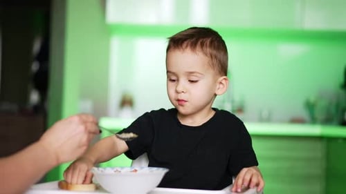 Child Being Fed in a Green Kitchen