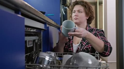 Woman Takes Out Clean Dishes After Washing in Dishwasher