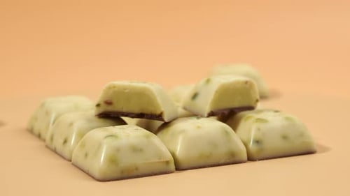 Rotating white chocolate with pistachios on an orange background.