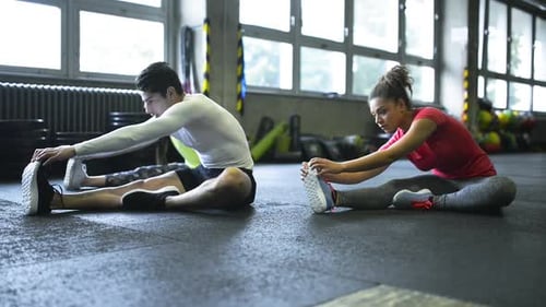 Young People in Gym Stretching Their Legs