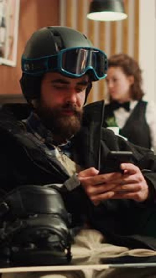 Man in Ski Gear Using Smartphone Indoors