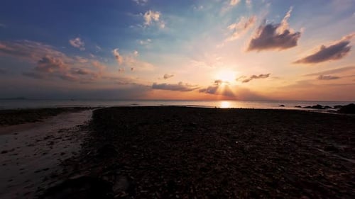 Wide Aerial View of Rocky Tropical Shoreline at Sunset With Calm Ocean And Dramatic Clouds, Golden