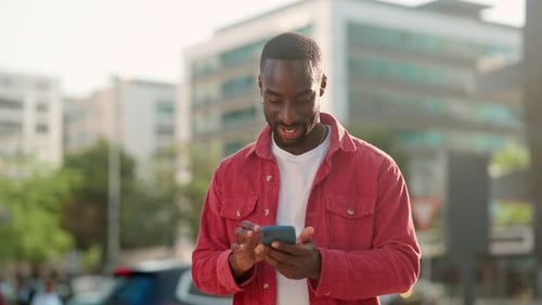 Happy Young African Black Man Standing on City Street Using Smartphone